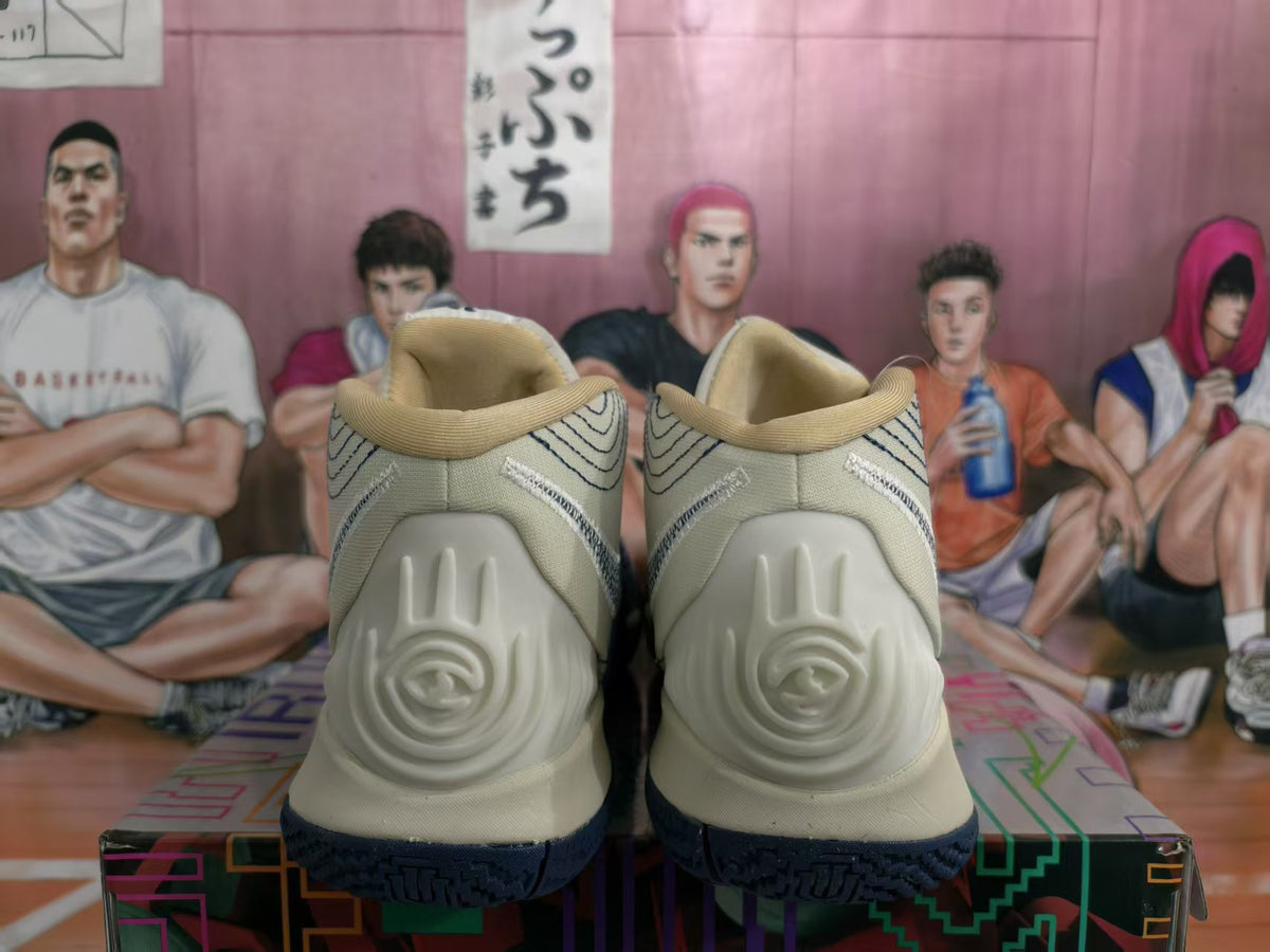 Rear view of off-white and navy high-top basketball sneakers showing the sculpted heel panels and textured dark outsole.
