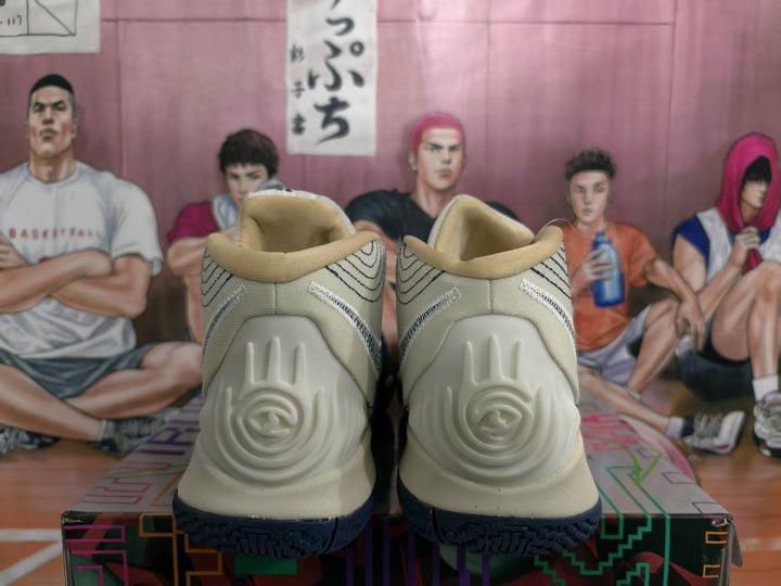 Rear view of off-white and navy high-top basketball sneakers showing the sculpted heel panels and textured dark outsole.