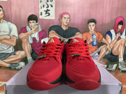 Front view of matching red basketball sneakers with red laces, black accents, and gold tongue branding.
