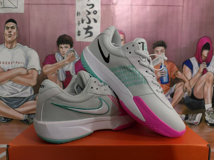 Pair of white Nike basketball sneakers with blue-green and pink accents displayed on an orange box.