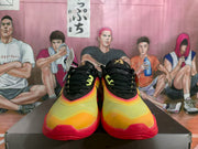 Front view showing the orange and yellow toe areas, black laces, and red outsoles.