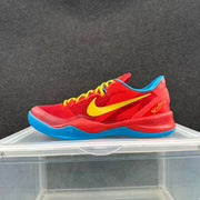 Side profile of a red Nike basketball sneaker with yellow Swoosh branding, blue outsole, and heel decoration.
