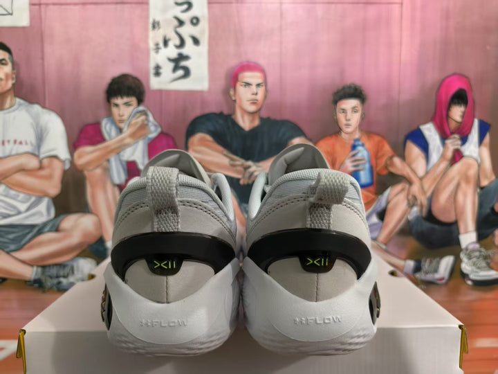 Rear view of gray and green basketball sneakers showing padded collars, pull tabs, black heel sections, and heel graphics.