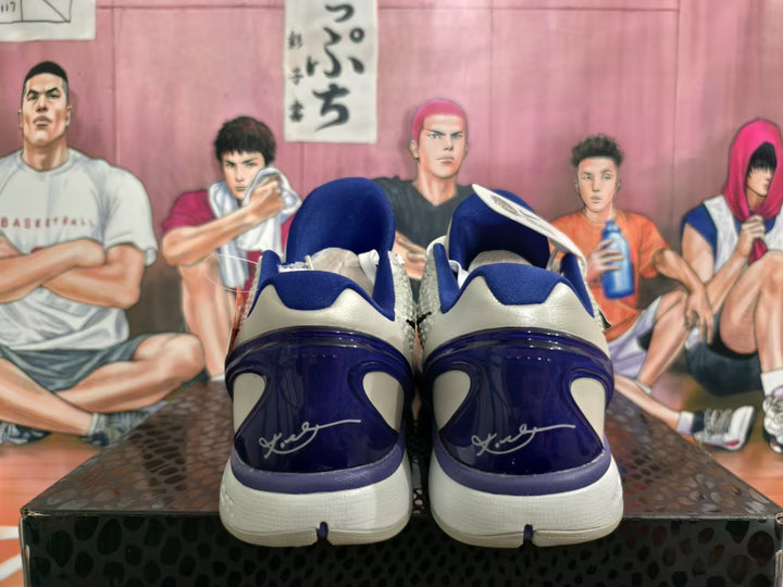 Rear view of white and purple Nike basketball shoes showing blue-purple heel panels and signature graphics.