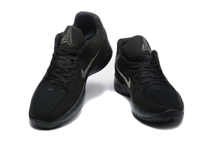 Pair of black low-top sneakers shown from the front, with rhinestone-style tongue and side accents.