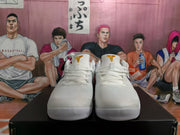 Front view of white lace-up basketball sneakers with gold tongue branding and textured uppers.