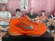 Side profile of an orange Nike basketball sneaker displaying the textured upper, silver Swoosh, sculpted midsole, and gum-toned outsole.