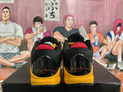 Rear view showing the red collar accents, glossy black heel panels, yellow midsoles, and script detailing.