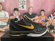 Side profile of one black basketball sneaker showing the textured upper, yellow Nike Swoosh, black midsole, and white outsole.