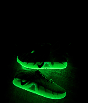 The sneakers shown glowing bright green in a dark setting.
