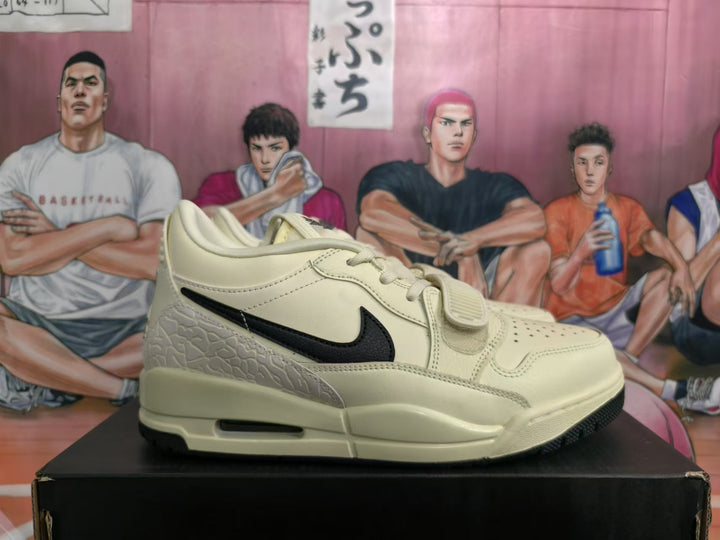 Side view of cream-and-black low-top sneakers with a midfoot strap and textured heel panel