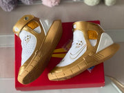 Angled top view showing both shoes, the gold ankle straps, white perforated uppers, and patterned outsoles.