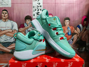Angled view showing the pale green Nike basketball sneakers, textured outsole, white midsole, and side detailing.