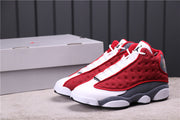 Pair of red, gray, and white Air Jordan 13 sneakers beside a shoebox.
