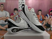 Angled view of the paired white and black sneakers showing the side emblem, black heel details, and layered soles.