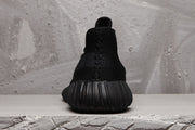Rear view of a black Yeezy 350 V2 sneaker showing the rounded heel and ribbed sole.
