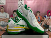 Angled view of the pair highlighting the textured white upper, green Nike branding and yellow midsole accents.
