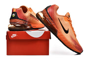 Orange Nike sneakers displayed beside a red shoe box.