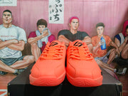 Pair of orange low-top basketball sneakers shown from the front, with perforated toes and black Jumpman tongue branding.