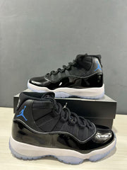 Close angled view of the pair highlighting the black glossy panels, black laces, blue branding, and white midsoles.