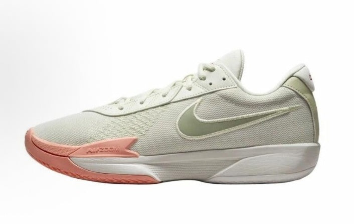 Side view of a light olive Nike low-top sneaker with white detailing, a coral-pink forefoot accent, visible Swoosh, and Zoom branding.