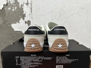 Rear view of cream Converse sneakers with black heel tabs and gum-colored soles