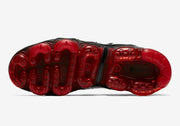 Underside view of a Nike Air VaporMax Plus sneaker with a translucent red outsole.