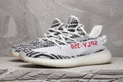 Pair of black-and-white knit sneakers shown from a three-quarter side angle with white laces and red side lettering.