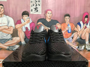 Front view of the black basketball sneakers showing the textured toe box, black laces, metallic gray tongues, and red Kobe-style tongue logos.