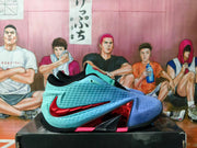 Side view of a Nike basketball shoe with an aqua and blue upper, red Swoosh and black outsole.