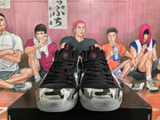 Front view of black lace-up sneakers with gray, white, and black camouflage-style toe panels.
