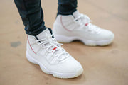 Worn front-side view of the white sneakers on a light floor.