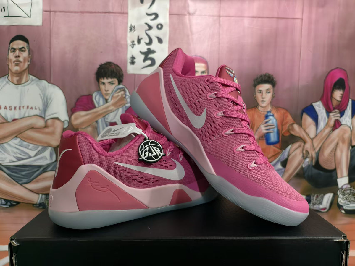 Pair of pink Nike basketball sneakers displayed on a black shoebox, showing the side swoosh, layered pink panels, and translucent-looking soles.