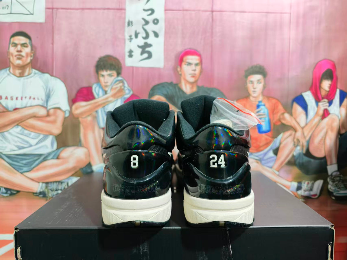 Rear view of black high-top basketball sneakers showing the numbers 8 and 24 on the heels, displayed on a black shoebox.