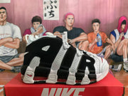 Side view highlighting the layered black and white upper, perforated panels, large AIR lettering, and red-tinted sole cushioning.