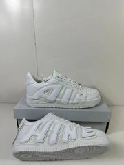 White low-top sneaker pair showing oversized raised side lettering and the textured outsole.