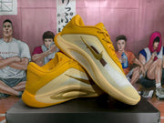 Pair of yellow and cream Nike basketball shoes shown at an angle on a black shoebox.
