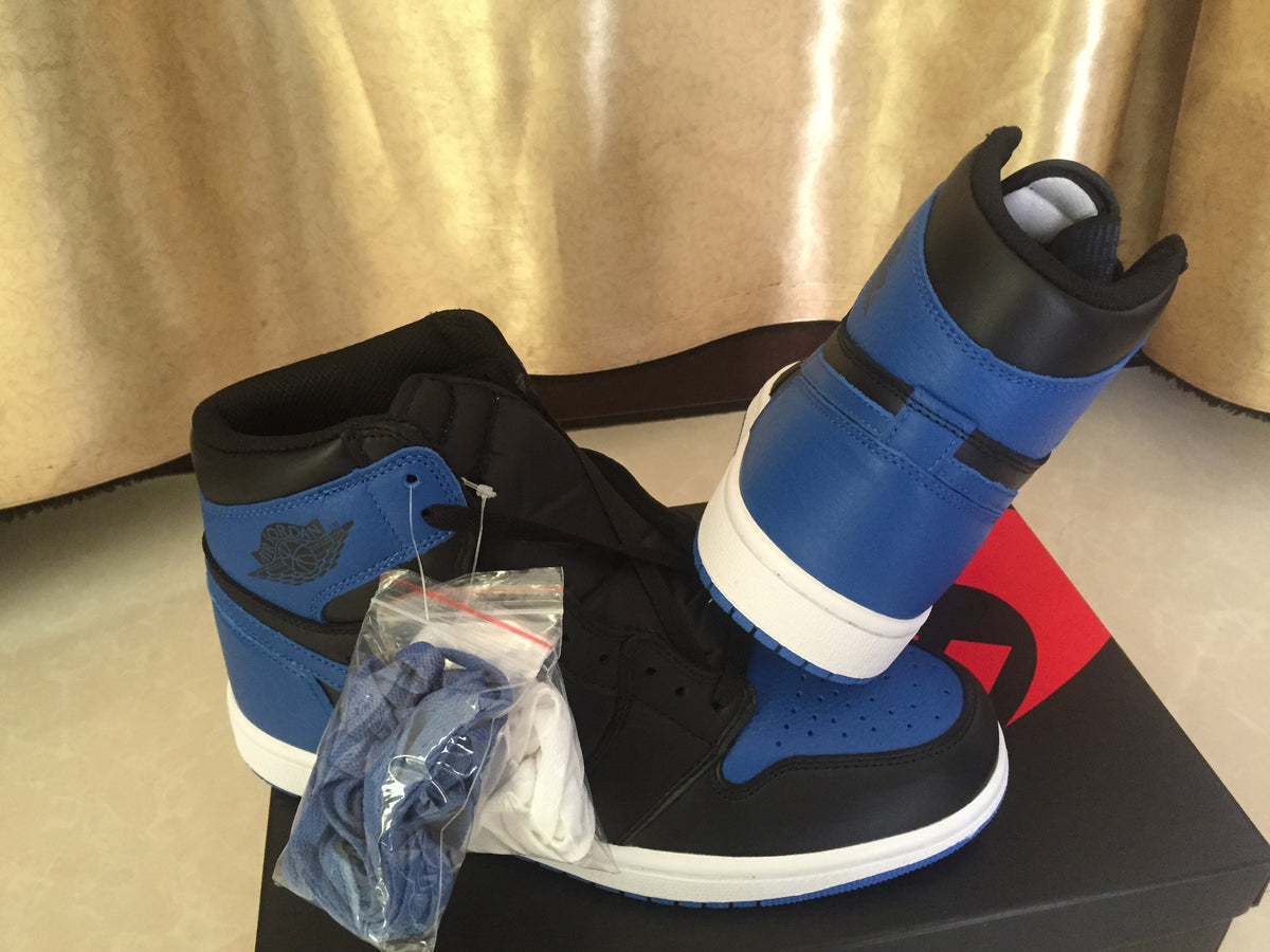 Black and royal blue high-top sneakers displayed on a Nike shoebox with extra laces in a clear bag.