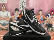 Angled view of black basketball shoes showing the white side logo, patterned upper, and gold number 2 detail