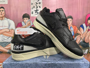 Angled view of two black Nike sneakers showing the side swoosh, perforated toe panel, padded tongue, and cream-colored outsole.