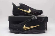 Black Nike Kobe 11 low-top shoes with gold Swoosh details displayed on a black box.