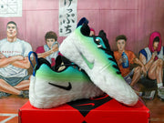 Angled view showing the pair's green gradient uppers, black laces, blue heel tabs and side Swoosh branding.