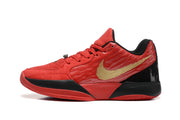 Side profile of a red basketball shoe with gold side logo and black accents
